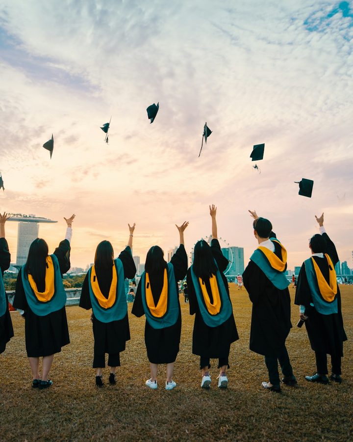 Graduates throwing their caps in the air at sunset