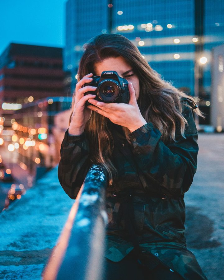 A photographer framing a shot with her camera at dusk
